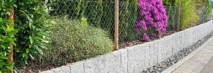 Gartenmauer aus Granitsteinen mit Maschendrahtzaun